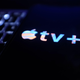 A phone with the apple TV+ logo sitting on top of a macbook keyboard.